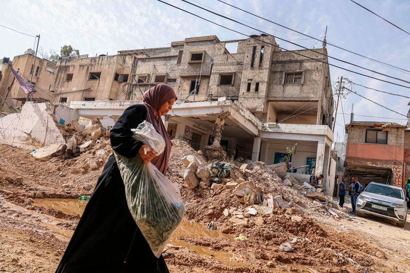 A woman walks past rubble as UN workers conduct rehabilitation works in the vicinity of the damaged UN agency for Palestinian refugees’ UNRWA headquarters at the Nur Shams refugee camp east of Tulkarem in the occupied West Bank - AFPpix