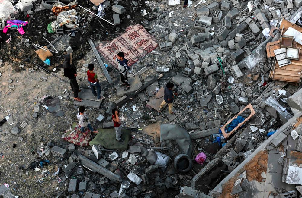 Palestinians children on May 6, 2019, gather among the rubble of a building that was destroyed during Israeli airstrikes on Gaza City. — AFP