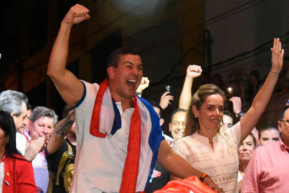 Paraguayan presidential candidate for the Colorado Party, Santiago Peña (C), celebrates with supporters accompanied by his wife, Leticia Ocampos de Pea (L), after winning the presidential election in Asuncion on April 30, 2023. AFPPIX