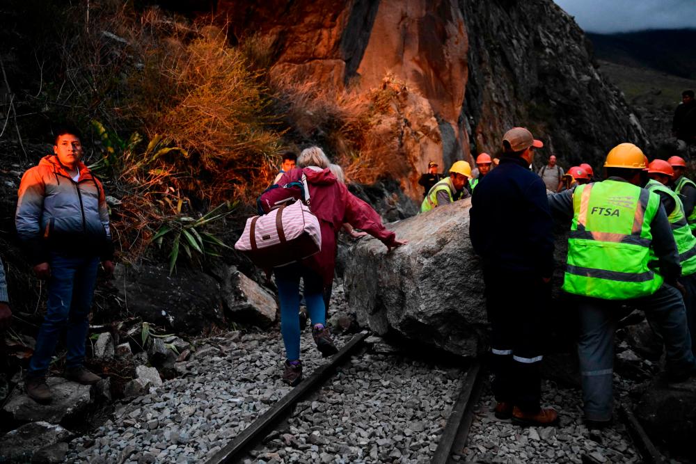 A stranded tourist who was visiting the Inca citadel of Machu Picchu walks next to a rock blocking the railway track after being evacuated by train to Ollantaytambo, Peru, on December 17, 2022. AFPPIX
