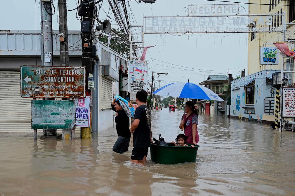 People wade through a flooded street in Kawit, Cavite province on October 30, 2022, a day after Tropical Storm Nalgae hit. AFPPIX