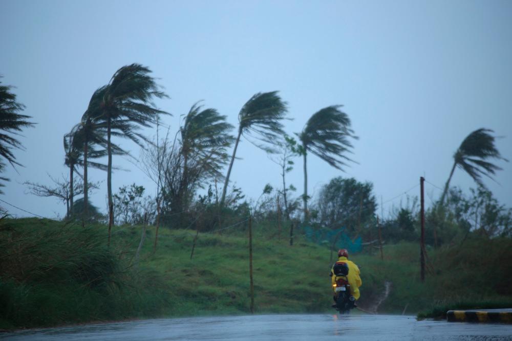 TOPSHOT - A motorist passes along a street amidst strong winds in Legazpi City, Albay province on November 11, 2020, ahead of the landfall of Tropical Storm Vamco -- expected to intensify into a typhoon -- in the region devastated by two typhoons in less than three weeks. AFPPIX