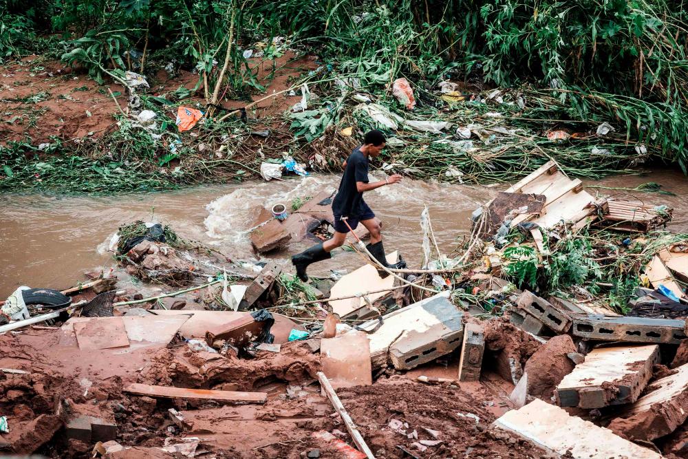 A man tries to retrieve some of his furniture at an informal settlement of BottleBrush, south of Durban, after torrential rains and flash floods destroyed his home on April 23, 2019. — AFP
