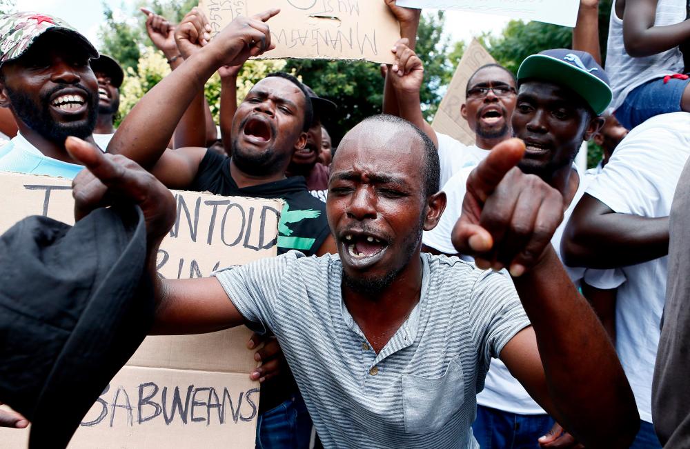 Protesters sing during a demonstration of Zimbabwean citizens outside the Zimbabwean Embassy in Pretoria on Jan 16, 2019, following the announcement of a petrol price hike in Zimbabwe and the recent shut down of mobile phone networks and internet services. — AFP