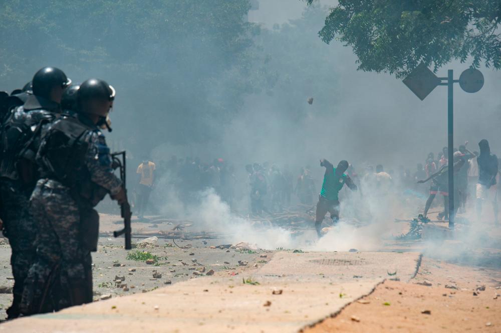 Supporters of opposition leader, Ousmane Sonko throw stones while police fire tear gas in Dakar on June 1, 2023, during unrest following the sentence of opponent Ousmane Sonko. AFPPIX