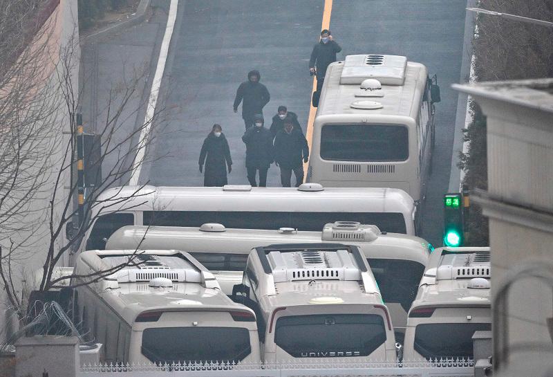 Security personnel walk on the road with buses blocking an entrance gate to protect impeached South Korean President Yoon Suk Yeol from a possible second arrest attempt by the Corruption Investigation Office for High-ranking Officials inside the compound of the presidential residence in Seoul on January 6, 2025. South Korean investigators trying to arrest suspended President Yoon Suk Yeol have less than 24 hours before their warrant expires on January 6, with the embattled leader holed out in his residence surrounded by loyal security forces. - JUNG YEON-JE / AFP