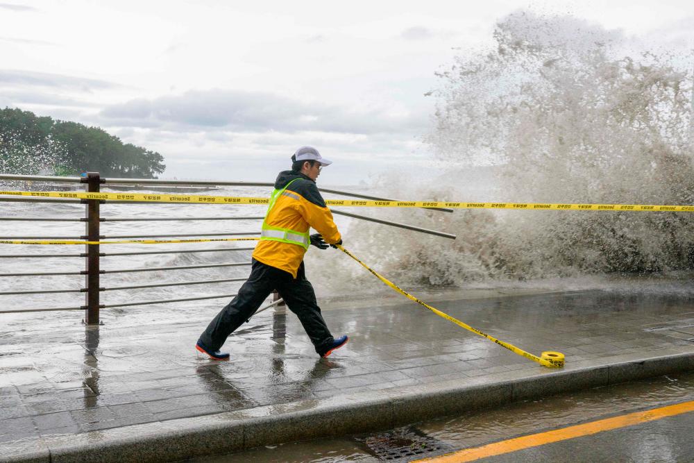 TOPSHOT - A worker puts up a safety cordon after Typhoon Hinnamnor passed through Busan on September 6, 2022. - AFPPIX
