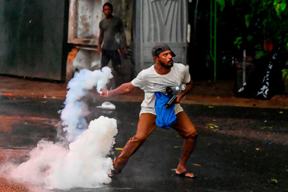 A demonstrator throws back a tear gas canister fired by police to disperse students taking part in an anti-government protest demanding the resignation of Sri Lanka’s President Gotabaya Rajapaksa over the country’s crippling economic crisis, in Colombo on May 29, 2022. AFPPIX