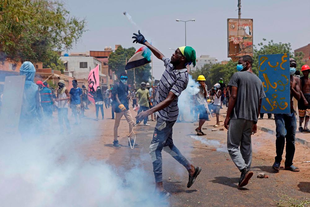 An anti-coup protester throws back a tear gas canister at security forces during clashes amdist mass demonstrations against military rule in the centre of Sudan’s capital Khartoum on June 30, 2022. AFPPIX