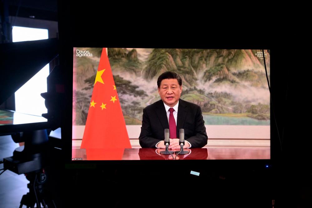 Chinese President Xi Jinping is seen on a TV screen speaking remotely at the opening of the WEF Davos Agenda virtual sessions at the WEF’s headquaters in Cologny near Geneva on January 17, 2022. AFPPIX