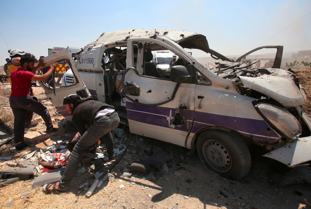 Syrian rescuers help a badly wounded fellow rescuer following a reported regime air strike which targeted an ambulance in the town of Maaret al-Numan in northwest Syria on June 20, 2019. — AFP