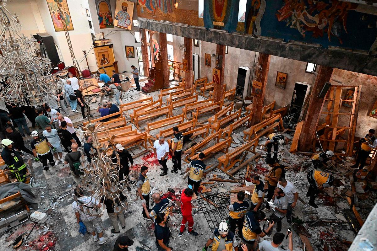 People and rescuers inspect the damage at the site of a reported suicide attack at the Saint Elias church in Damascus’ Dwelaa area on June 22, 2025. Syrian state media reported a suicide attack on a Damascus church on June 22 that caused casualties, as AFP correspondents at the scene saw first responders transporting people from the site. - LOUAI BESHARA / AFP