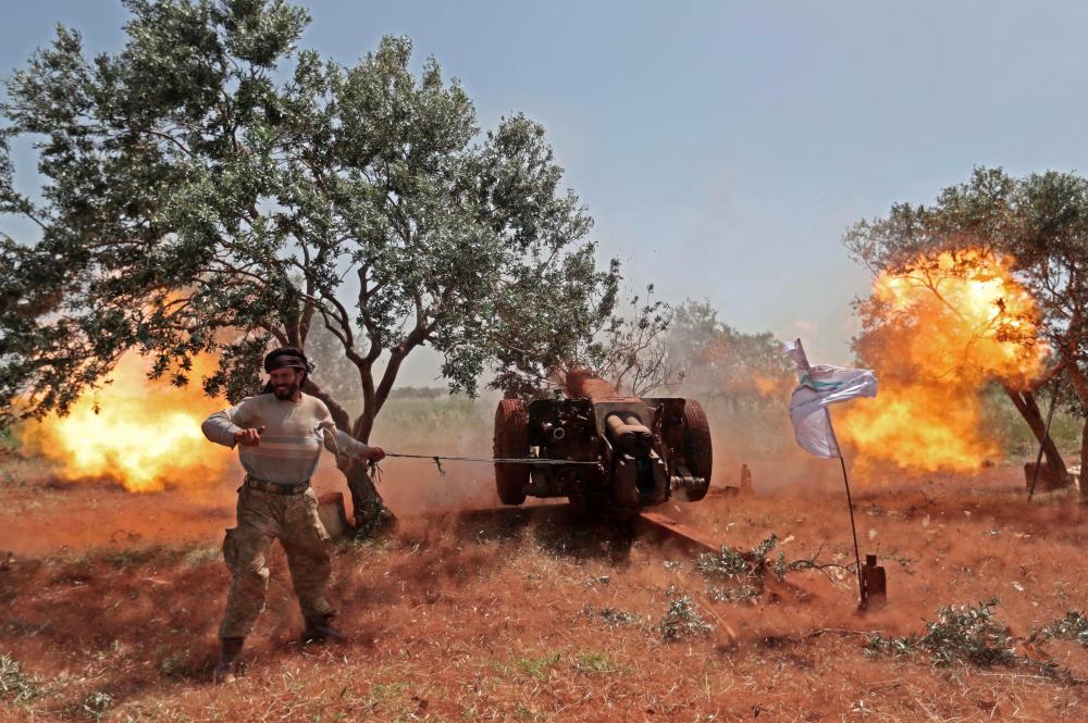 A Syrian fighter from the Turkish-backed National Liberation Front (NLF) fires a heavy artillery gun from the rebel-held Idlib province against against regime positions in the northern part of Hama province, on May 22, 2019. — AFP