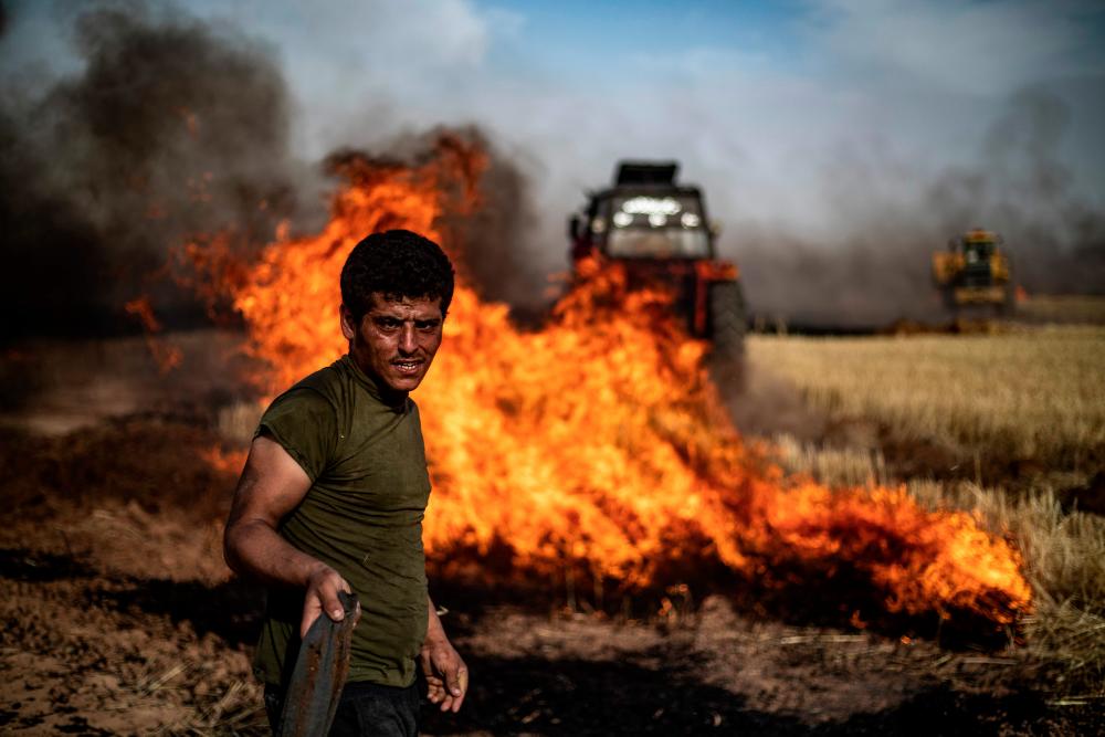 People battle a blaze in an agricultural field in the town of al-Qahtaniyah, in the Hasakeh province near the Syrian-Turkish border on June 10, 2019. Fires have erupted in various parts of Syria in recent weeks, with all sides blaming each other for starting them. In the Kurdish-run breadbasket province of Hasakeh, of which Al-Qahtaniya is part, IS has claimed several arson attacks on wheat fields. — AFP