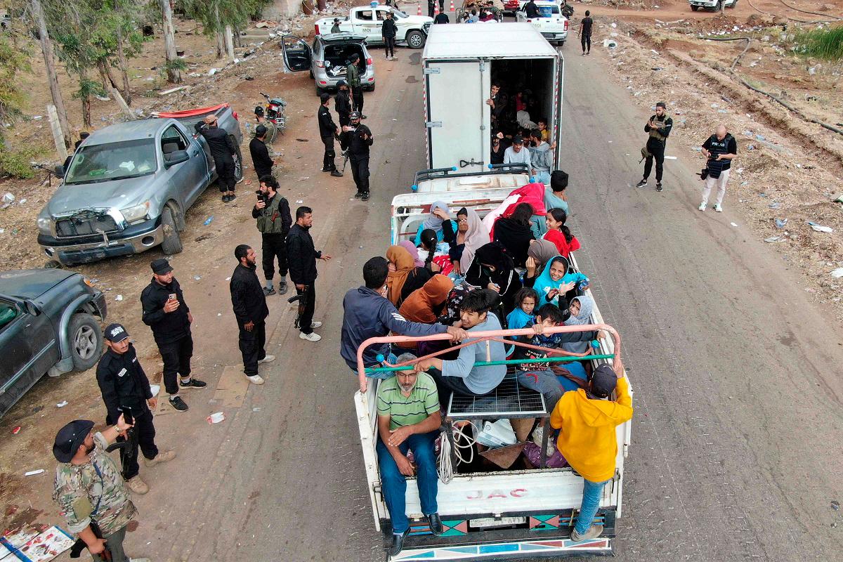This aerial view shows a truck carrying evacuating members of the Bedouin community stopping at a checkpoint set up by Syrian government forces along a road in Taarah, in Syria’s southern Sweida province on the way to Daraa, on July 21, 2025. Calm returned to southern Syria’s Sweida province on July 20, a monitor and AFP correspondents reported, after a week of sectarian violence between Druze fighters and rival groups that killed more than 1,100 people. - Rami al SAYED / AFP