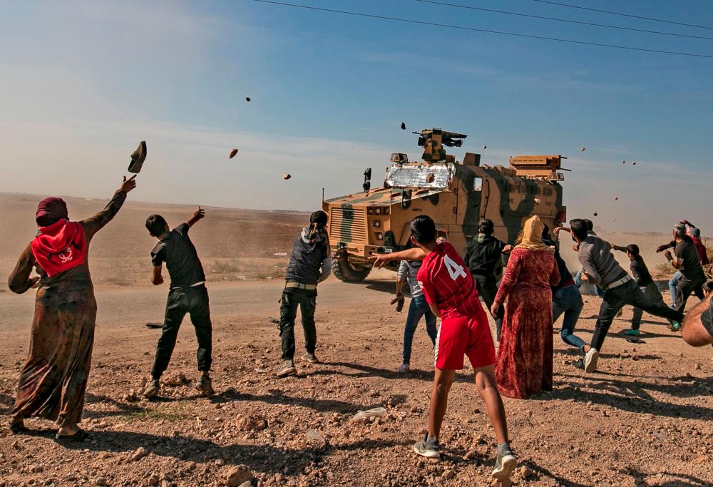 Syrians throw stones towards Turkish military vehicles during a Turkish-Russian army patrol near the town of Darbasiyah in Syria's northeastern Hasakeh province along the Syria-Turkey border on Nov 11. — AFP