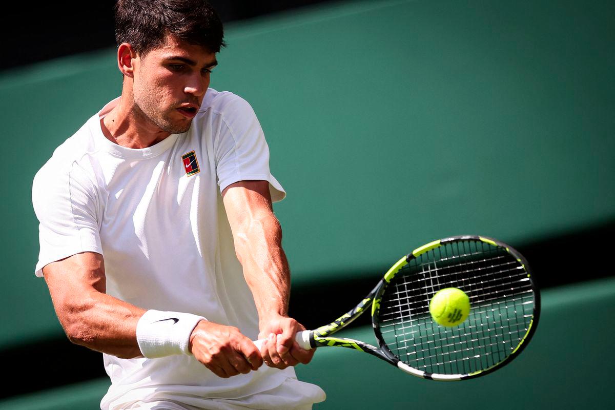 Spain's Carlos Alcaraz plays a backhand return to Italy's Fabio Fognini during their men's singles first round tennis match on the first day of the 2025 Wimbledon Championships at The All England Lawn Tennis and Croquet Club in Wimbledon, southwest London, on June 30, 2025. - AFPPIX