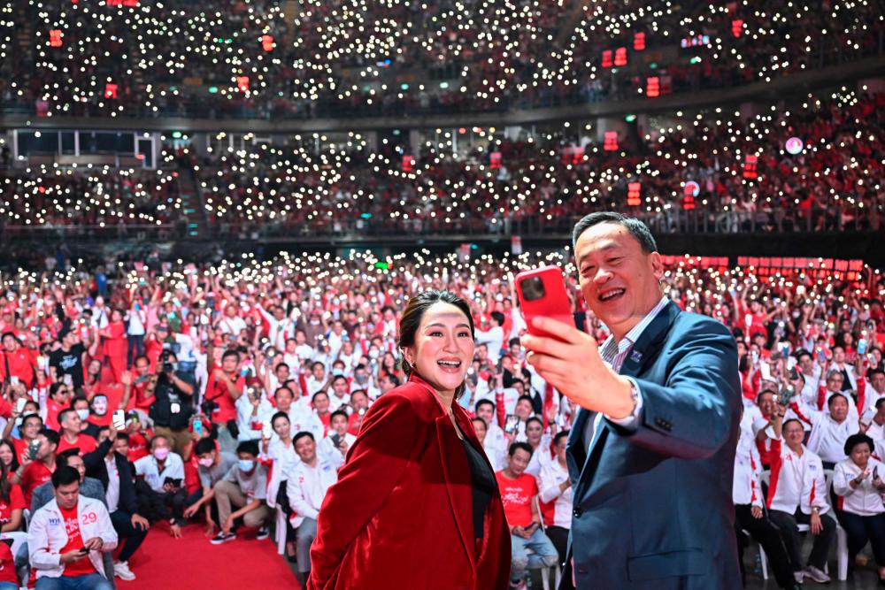 Pheu Thai Party’s prime ministerial candidates Paetongtarn Shinawatra (L) and Srettha Thavisin (R) take a selfie photo on stage at the party’s final campaign event in Bangkok on May 12, 2023, ahead of Thailand’s May 14 general election. AFPPIX