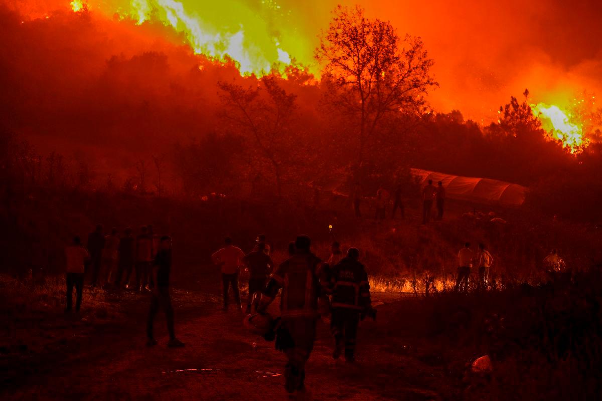 Residents and firefighters attempt to extinguish a wildfire as smoke and flames rise from a forested area in the Gursu district of Bursa early on July 27, 2025. (Photo by ONUR YURTSEVER / AFP)