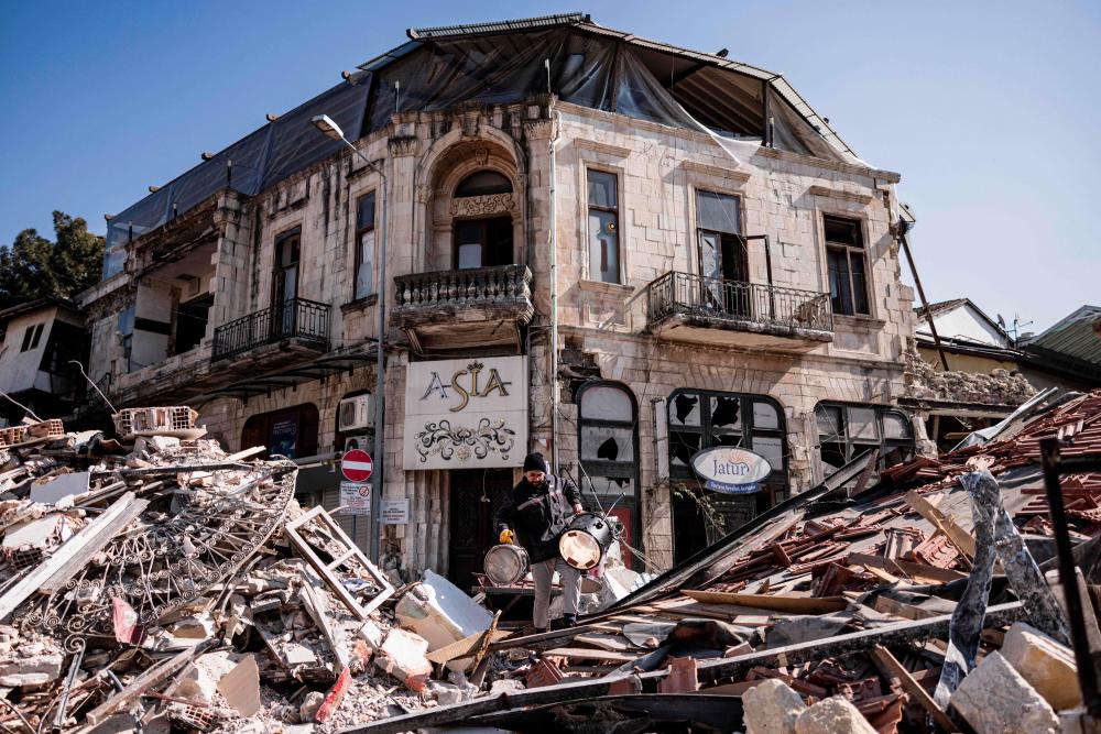 TOPSHOT - A man carries musical instruments out of the his damaged shop in Antakya on February 18, 2023. A 7.8-magnitude earthquake hit near Gaziantep, Turkey, in the early hours of February 6, followed by another 7.5-magnitude tremor just after midday. - AFPPIX