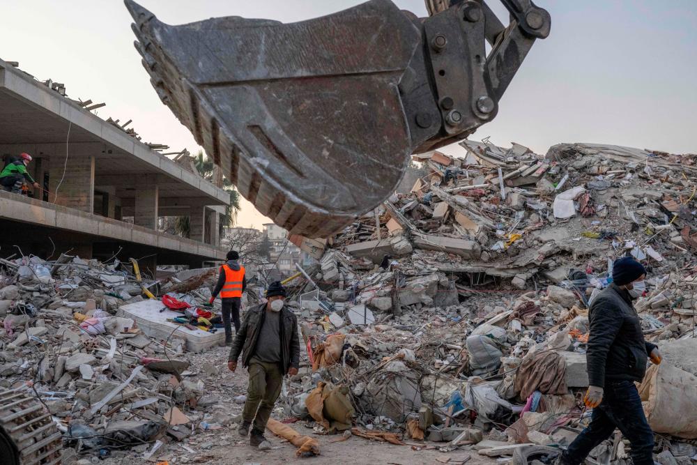 People walk in the rubble of destroyed buildings in Hatay on February 12, 2023, after a 7,8 magnitude earthquake struck the border region of Turkey and Syria earlier in the week/AFPPix