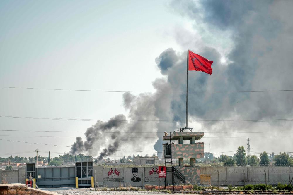 A picture taken in Akcakale at the Turkish border with Syria on Oct 10, 2019, shows smokes rising from the Syrian town of Tal Abyad after a mortar landed in the garden of a Turkish government building in Akcakale. — AFP
