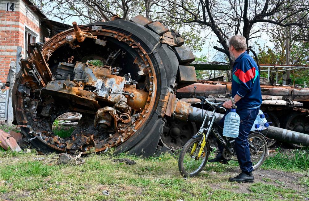 A local resident looks at a destroyed Russian tank next to a residential house in the village of Mala Rogan, east of Kharkiv, on May 15, 2022, amid Russian invasion of Ukraine. AFPPIX