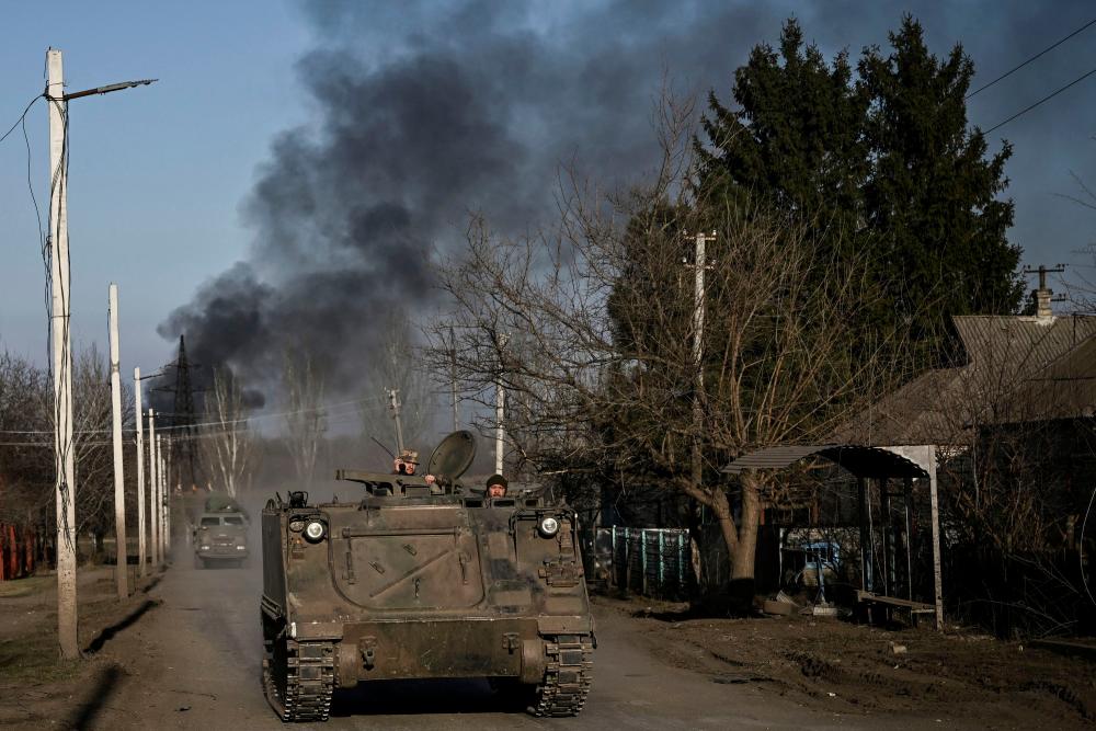 Ukrainian servicemen with a M113 armoured personnel carrier drive in the town of Chasiv Yar as smoke rises from the direction of Bakhmut on March 20, 2023. AFPPIX