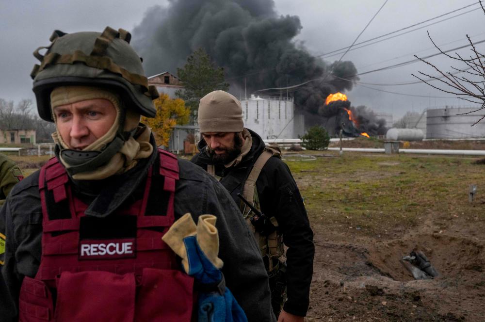 A Ukrainian rescue service member and a soldier inspect the area as black smoke rises from an oil reserve in Kherson on November 20, 2022, amid the Russian invasion of Ukraine. AFPPIX