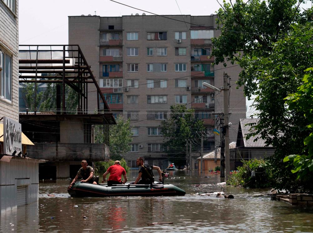 Ukrainian security forces ride in a boat during an evacuation from a flooded area in Kherson on June 7, 2023, following damages sustained at Kakhovka hydroelectric power plant dam. AFPPIX
