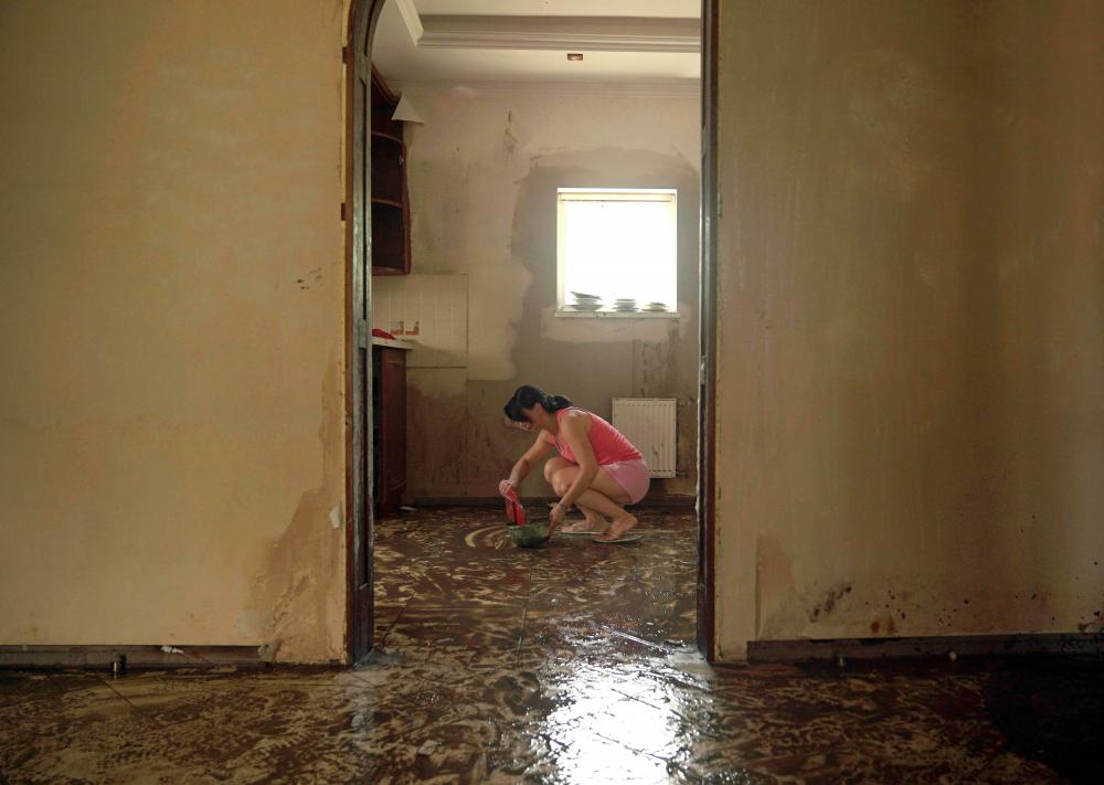 A local resident cleans mud off the floor in an apartment flooded by rising water following the collapse of the Kakhovka hydroelectric power plant dam, in Kherson on June 21, 2023. AFPPIX