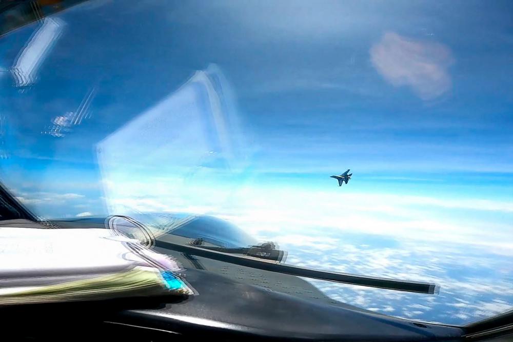 TOPSHOT - This screen grab made from video taken on May 26, 2023 and released on May 30 by the US Indo-Pacific Command via the Defense Visual Information Distribution Service (DVIDS) shows a J-16 fighter pilot from China flying in front of the nose of a US Air Force RC-135 aircraft over the South China Sea in international airspace. - AFPPIX
