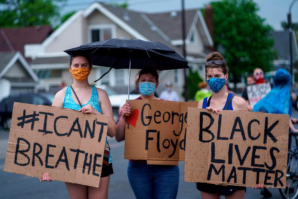 Women hold signs while protesting near the area where a Minneapolis Police Department officer allegedly killed George Floyd, on May 26, 2020 in Minneapolis, Minnesota. — AFP