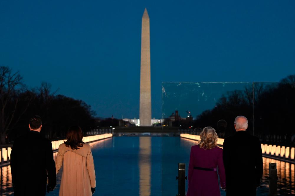TOPSHOT - US Vice President-elect Kamala Harris (2nd L) with husband Douglas Emhoff and US President-elect Joe Biden (R) with wife Dr. Jill Biden watch as a Covid-19 Memorial is lighted at the Lincoln Memorial in Washington, DC, on January 19, 2021 to honor the lives of those lost to Covid-19. / AFP / JIM WATSON