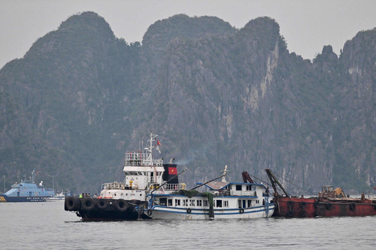 Bot pelancong (C) yang terbalik telah ditunda kembali ke pelabuhan di Teluk Hạ Long, Wilayah Quảng Ninh pada 20 Julai 2025. - AFP