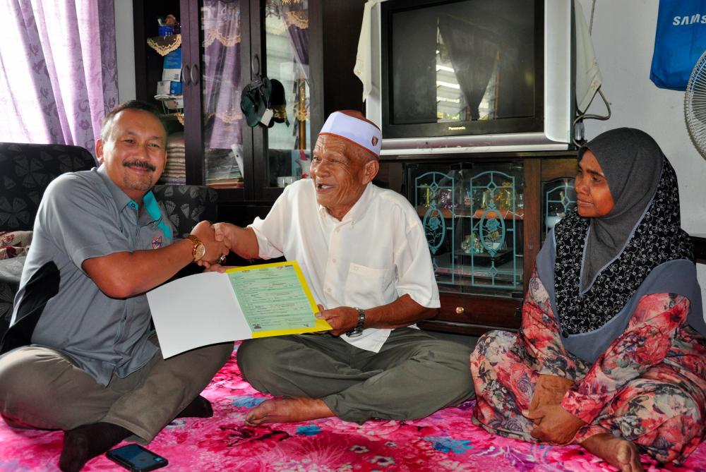 NRD director-general Datuk Ruslin Jusoh (L) presents a new birth certificate to Embong Muhamad, 71, a senior citizen who had no birth certificate and identity card for over 40 years, at Embong’s Kampung Lay Out Gerai, Jertih on May 4, 2019. - Bernama