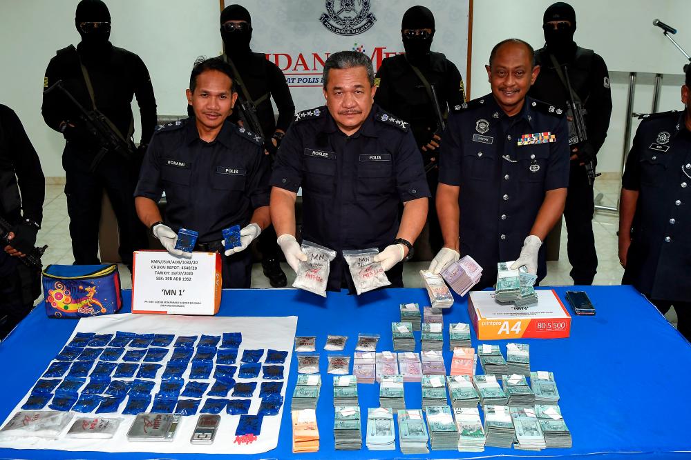 Terengganu police chief Datuk Roslee Chik (C) displays the drugs and cash seized from a drug syndicate, at the Kemaman District Police Headquarters today. - Bernama