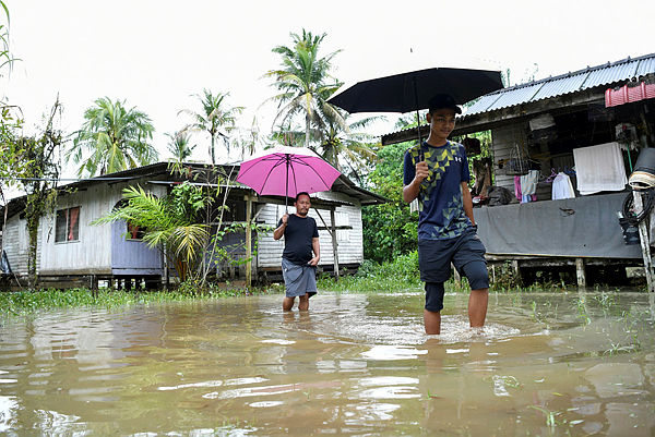 Flood victims wade through water at Kampung Tembak Baru, Wakaf Tapai today. — Bernama