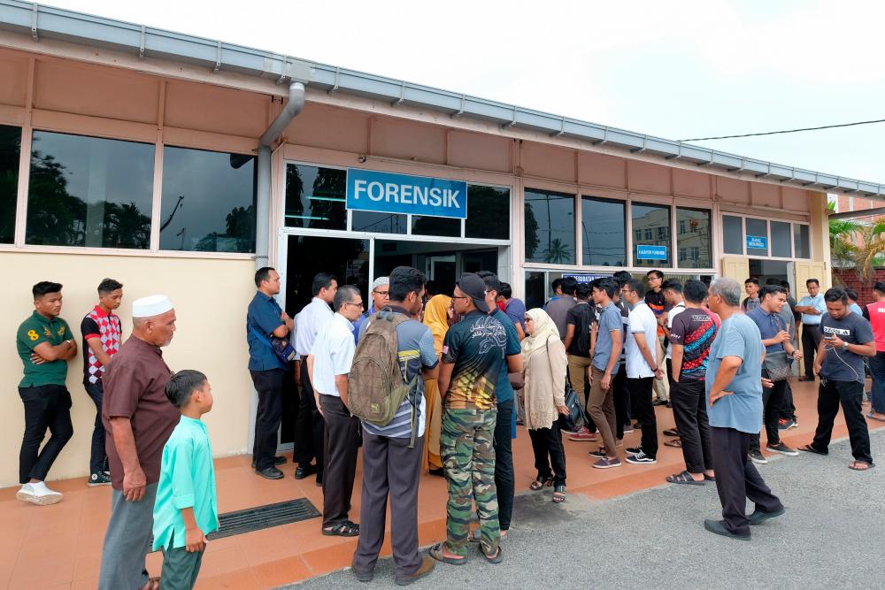Family members and friends of drowned Mohamad Amir Izzudin wait at the Dungun Hospital Forensic Unit to claim the remains today. - Bernama