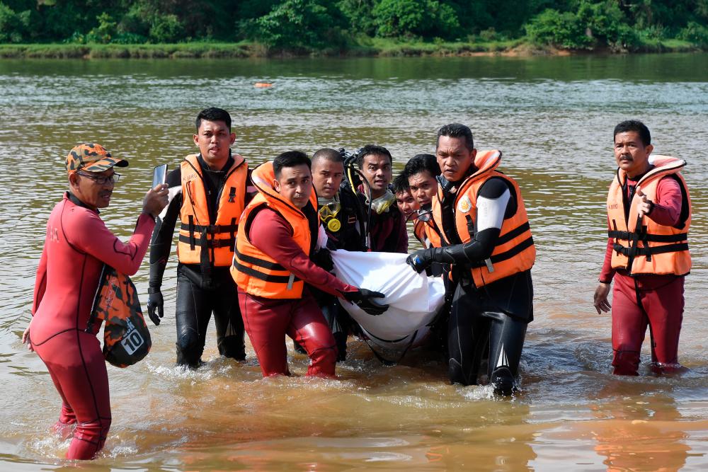 Terengganu Fire and Rescue Department personnel carry the body of one of three brothers feared drowned at Sungai Terengganu near Kampung Kuala Telemong here which was found today. — Bernama
