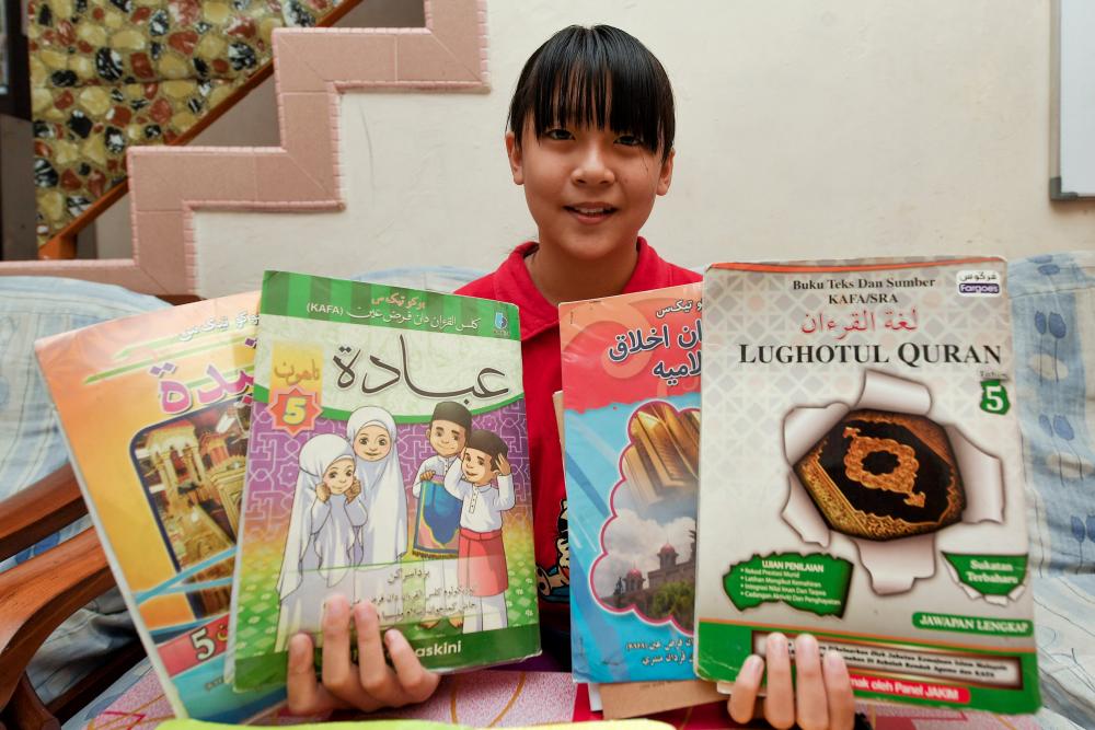 Chinese pupil Por Hui Ling, 11, from Sekolah Kebangsaan (SK) Tok Jiring holds up her exercise books during an interview at Taman Desa Jaya, Kuala Nerus, Terengganu on Dec 20, 2018. — Bernama