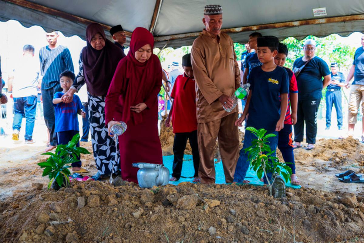 Isteri Allahyarham Koperal Mohd Hafizul Izham Mazlan, Nur Azhanis Mohd Yusof, 36, menyiram air pada pusara suaminya di Tanah Perkuburan Islam Putera Jaya, hari ini. - fotoBERNAMA