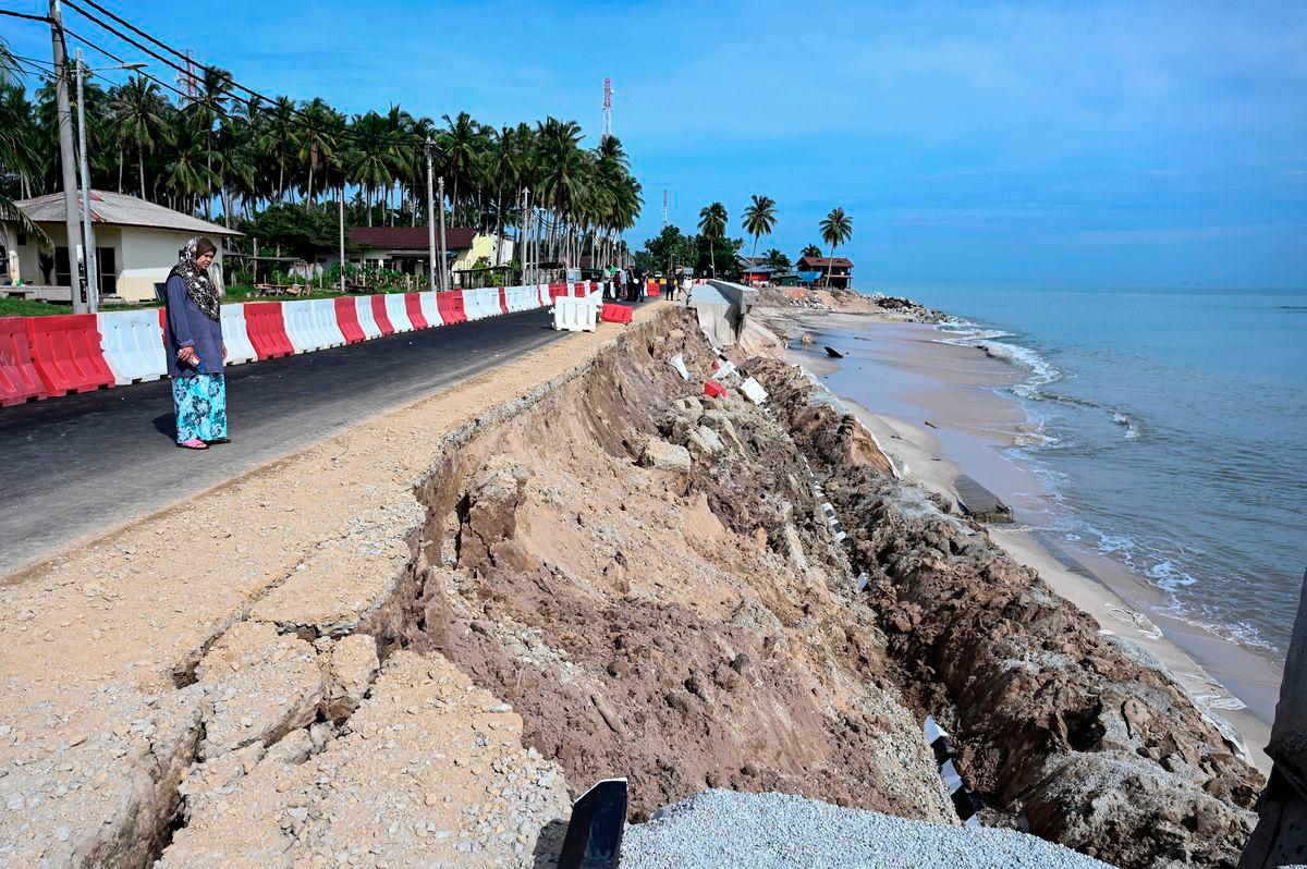 A resident, Maimun Johar, 56, surveys the aftermath of a collapsed embankment structure near her home, which sustained severe damage believed to have been caused by coastal erosion last night, during an inspection at Kampung Tanjung today. – BERNAMA