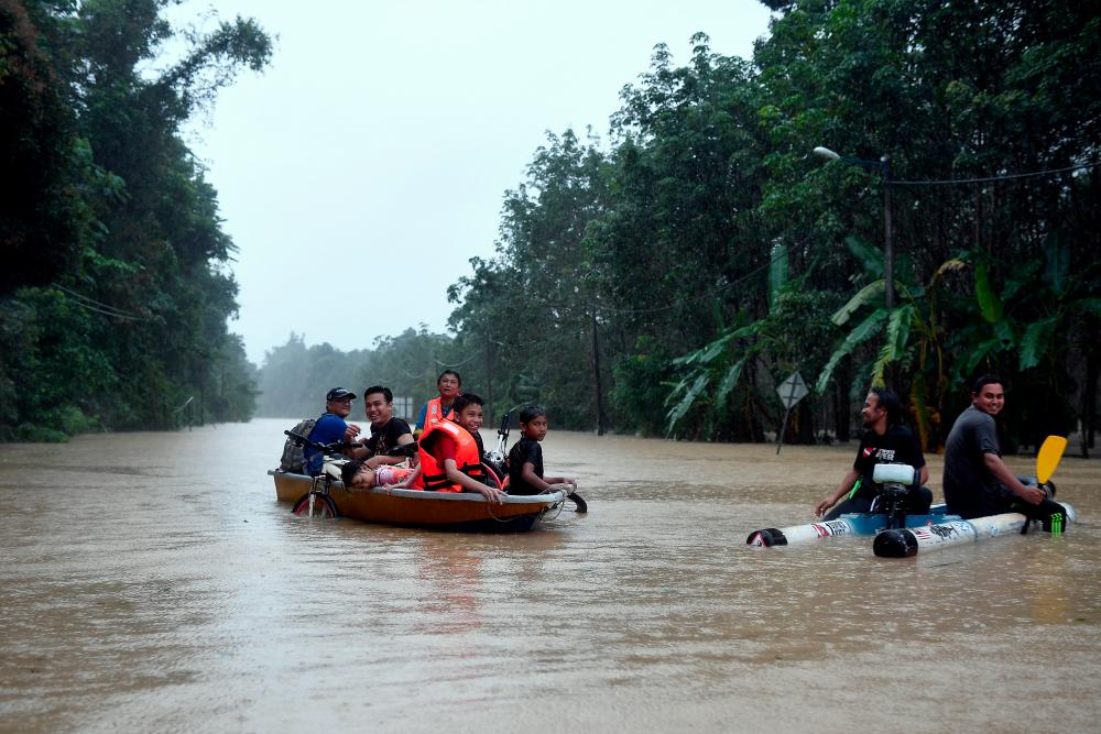 Flood victims use boat to commute from Kampung Bukit Payung to Kampung Keruak after the road connecting the two villages was cut off due to floods on Dec 2, 2019. — Bernama