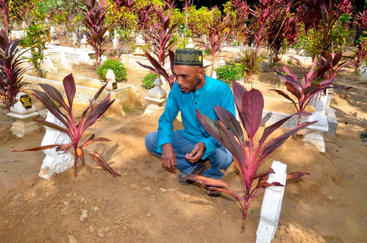 Fadli Abdul Rahman, 50, father of the late Fatin Nasrien, 22, recites a prayer at his daughter’s grave, who died in the tragedy near Tasik Banding last Monday, at the Kampung Kerandang Islamic Cemetery today. - BERNAMAPIC