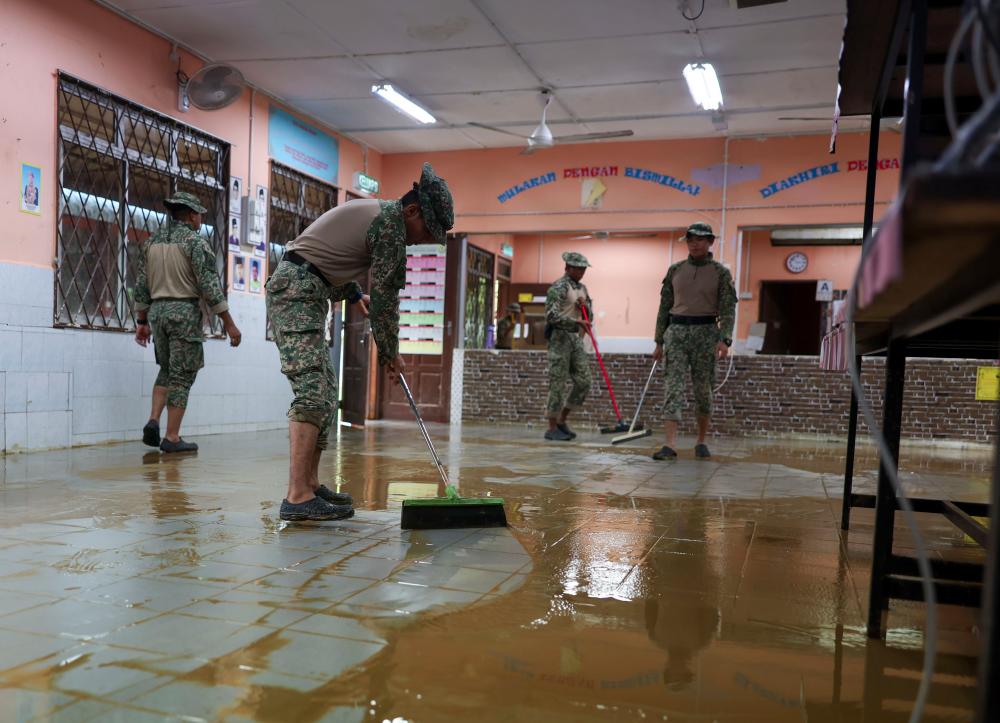 Anggota Angkatan Tentera Malaysia (ATM) membantu membersihkan kawasan Sekolah Kebangsaan Pasir Raja selepas dilanda banjir baru-baru ini ketika tinjauan di Kampung Pasir Raja hari ini. - fotoBERNAMA