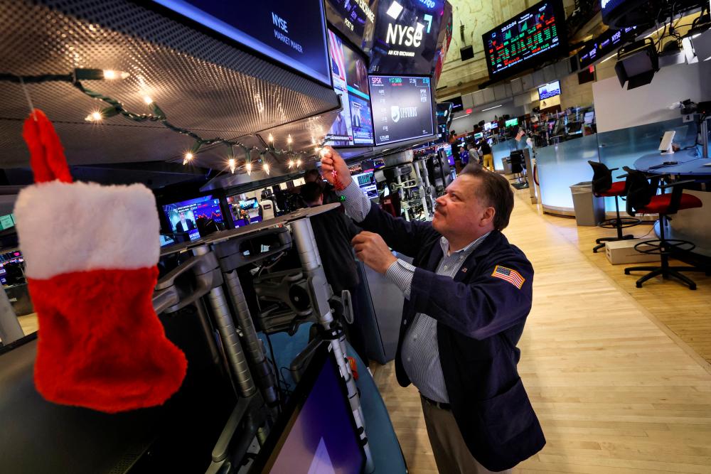 A trader hangs Christmas decorations on a trading post on the floor of the New York Stock Exchange on Tuesday. – Reuterspic