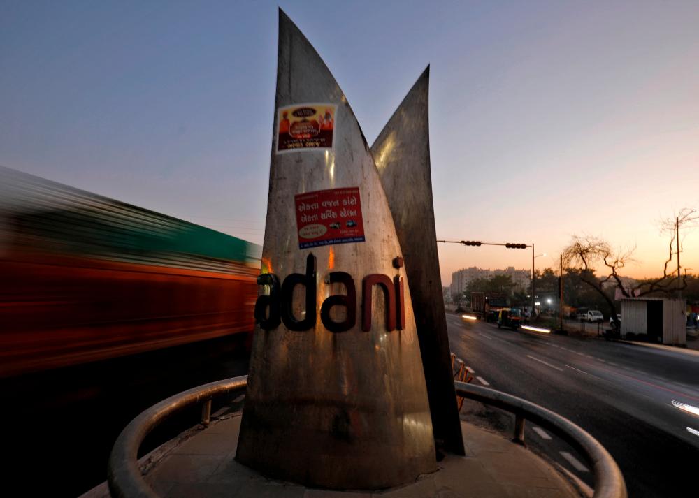 Traffic moves past the logo of the Adani Group installed at a roundabout on the ring road in Ahmedabad, India. – Reuterspic