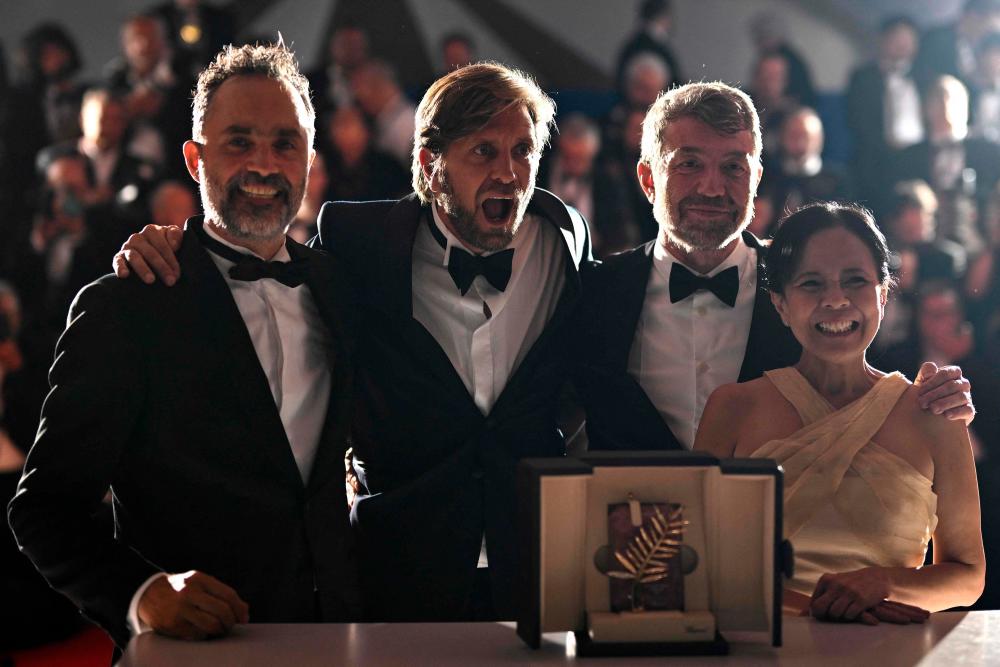 Swedish film director Ruben Ostlund (2L) poses with (from L) Swedish film producer Erik Hemmendorff, film producer Philippe Bober and Filipino actress Dolly de Leon during a photocall after he won the Palme d'Or for the film Triangle of Sadness during the closing ceremony of the 75th edition of the Cannes Film Festival in Cannes, southern France, on May 28, 2022. AFPpix