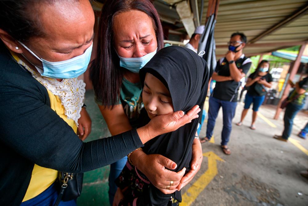 Family members console Fatihah Najwa Mohd Hamzah, 10, the younger sister of the drowning victim of the tragedy at the Triso Ferry Jetty, at the Forensic Unit of Sri Aman Hospital during the identification process here. — Bernama